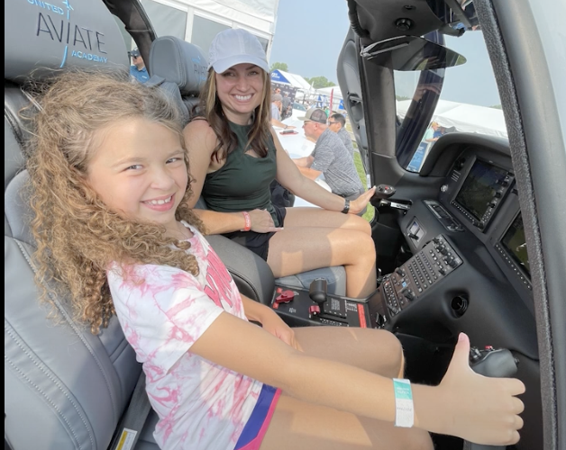 Mom and daughter sitting in plane smiling